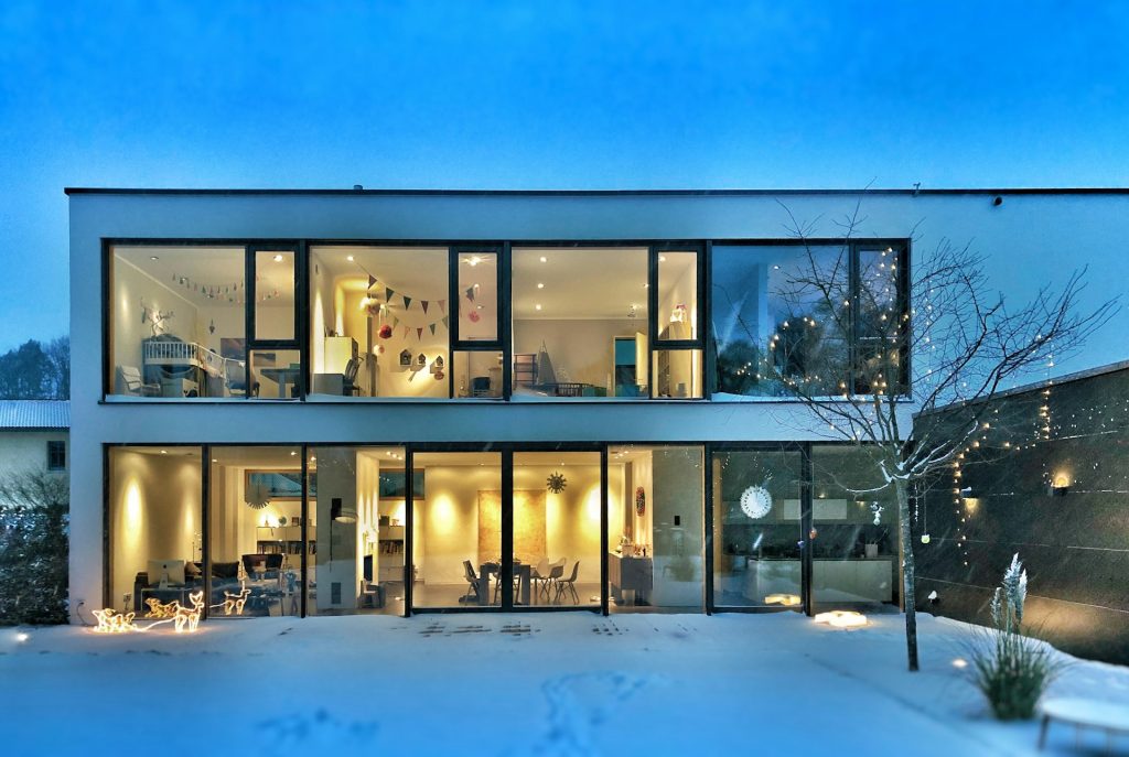 Modern home lit warmly on a snowy evening